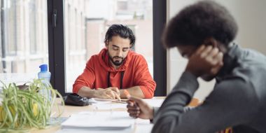 Twee cursisten zitten gebogen over hun cursus in een leslokaal