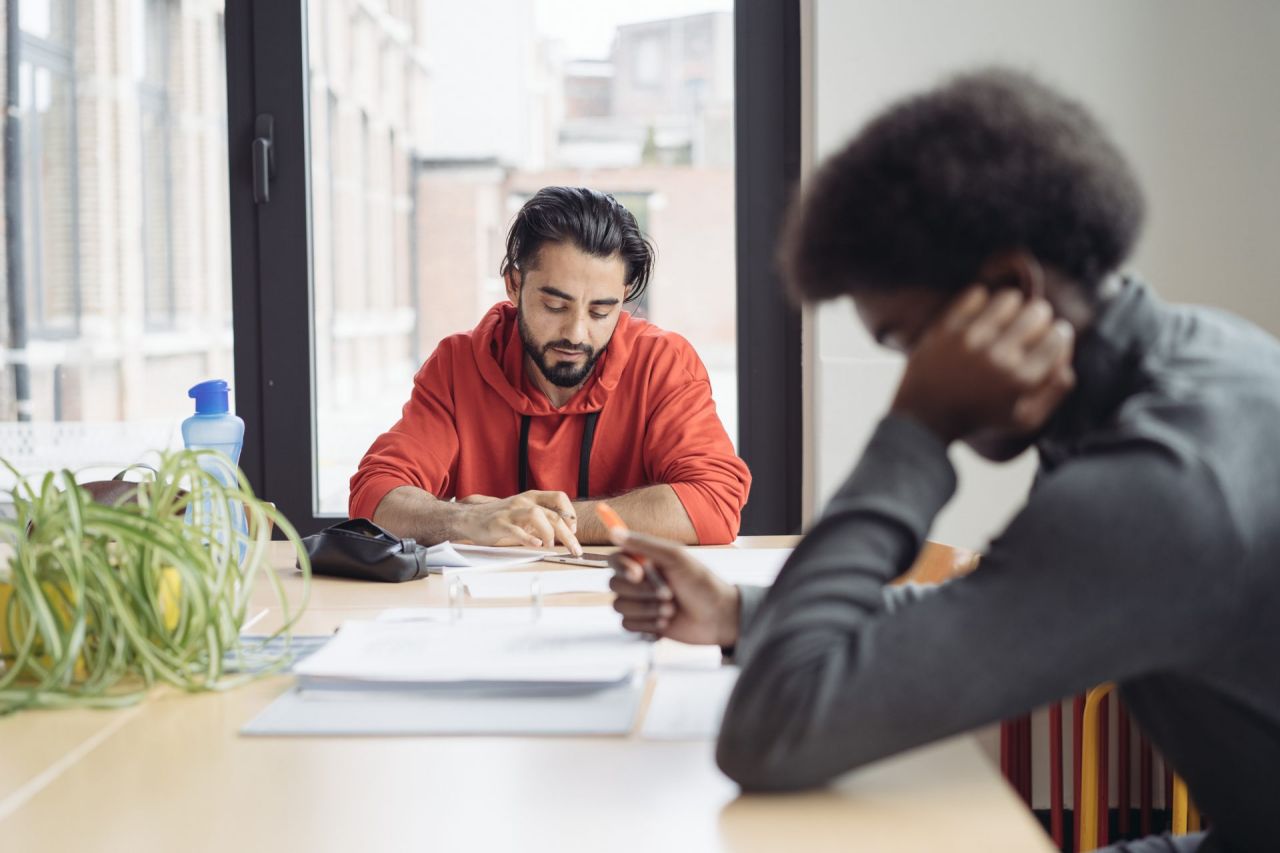 Twee cursisten zitten gebogen over hun cursus in een leslokaal